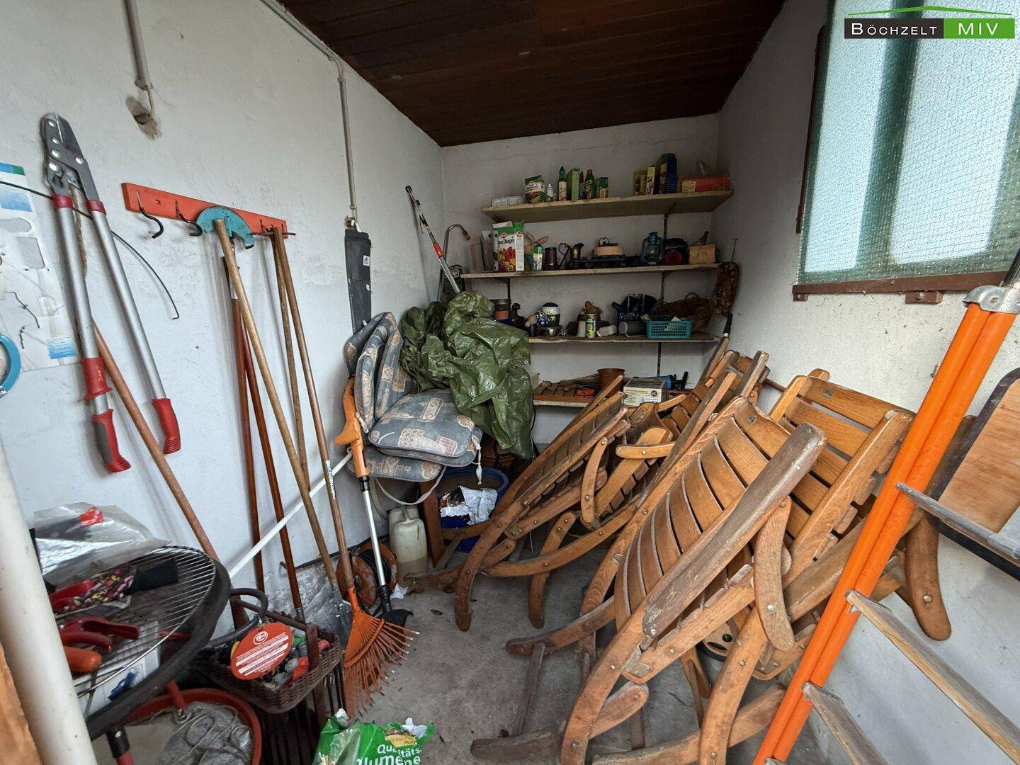 Geräteschuppen mit Gartenwerkzeugen und zusammengeklappten Gartenmöbeln, bereit für den Einsatz.
