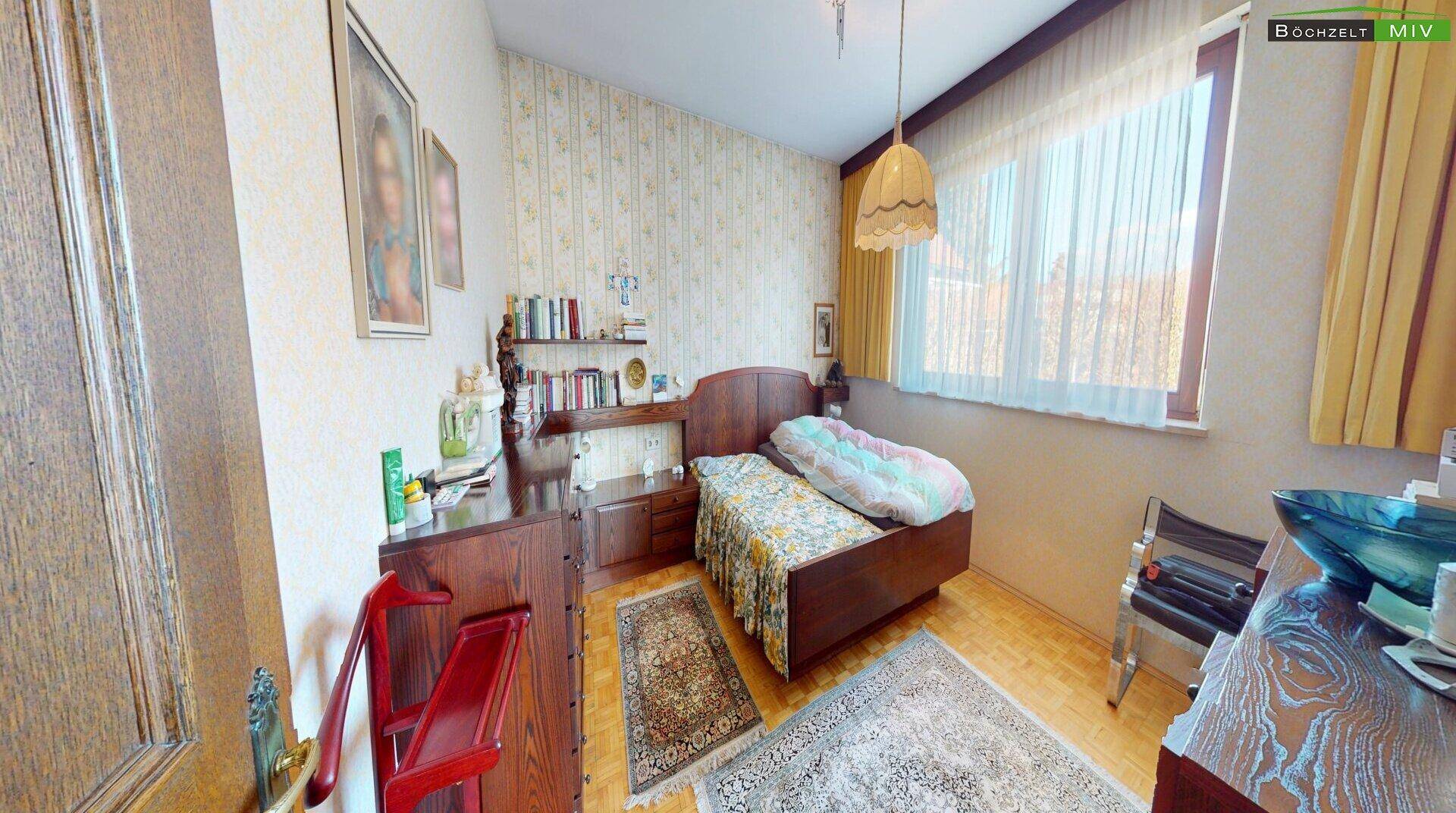 Gemütliches Schlafzimmer mit Einzelbett, Holzmöbeln und gemusterter Tapete.