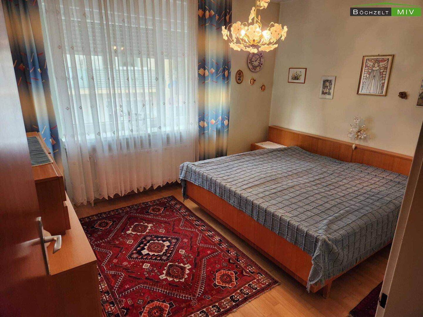 Gemütliches Schlafzimmer mit Doppelbett, Holzmöbeln und einem traditionellen Teppich.