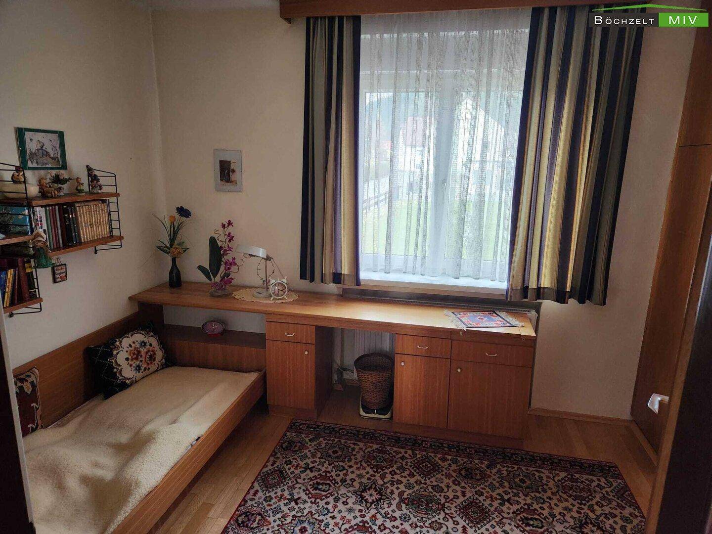 Helles Zimmer mit Einzelbett, Schreibtisch und Holzmöbeln, ideal als Gäste- oder Arbeitszimmer.