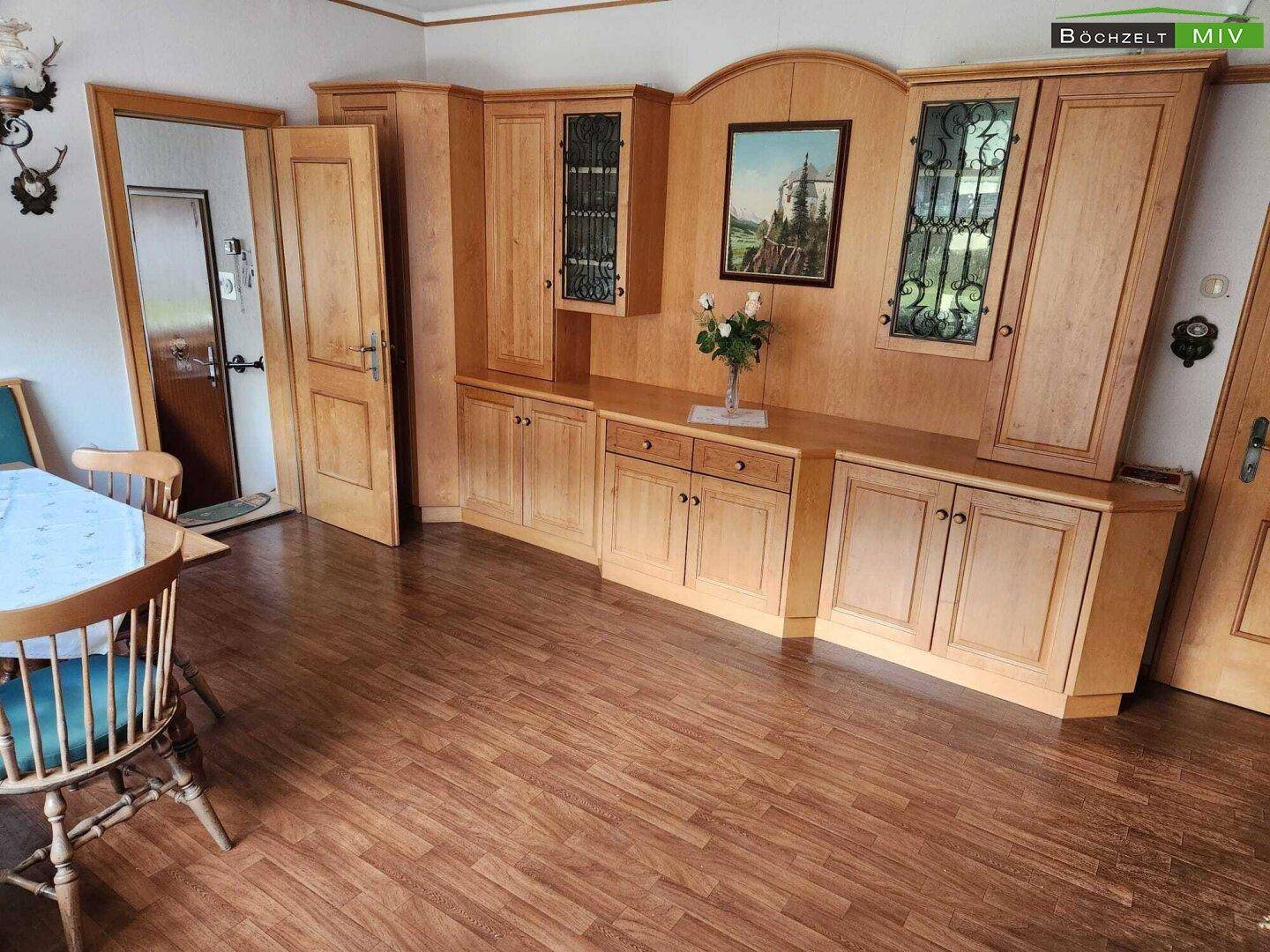 Wohnbereich mit rustikalen Holzschränken, Vitrinen und einem Holzboden in warmen Tönen.