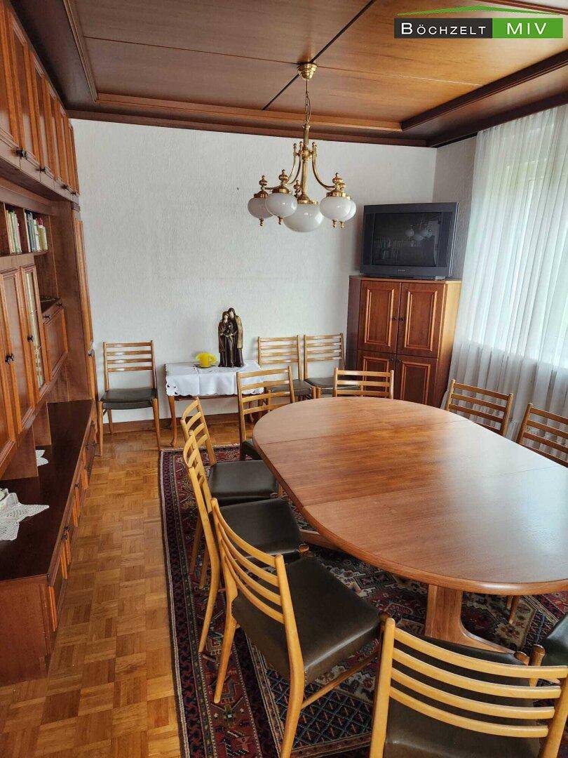 Geräumiger Essbereich mit großem Holztisch, vielen Stühlen und einer Holzdecke.