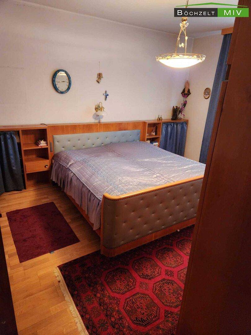 Schlafzimmer mit Doppelbett, Nachttischen und einem Teppich, in traditionellem Stil eingerichtet.