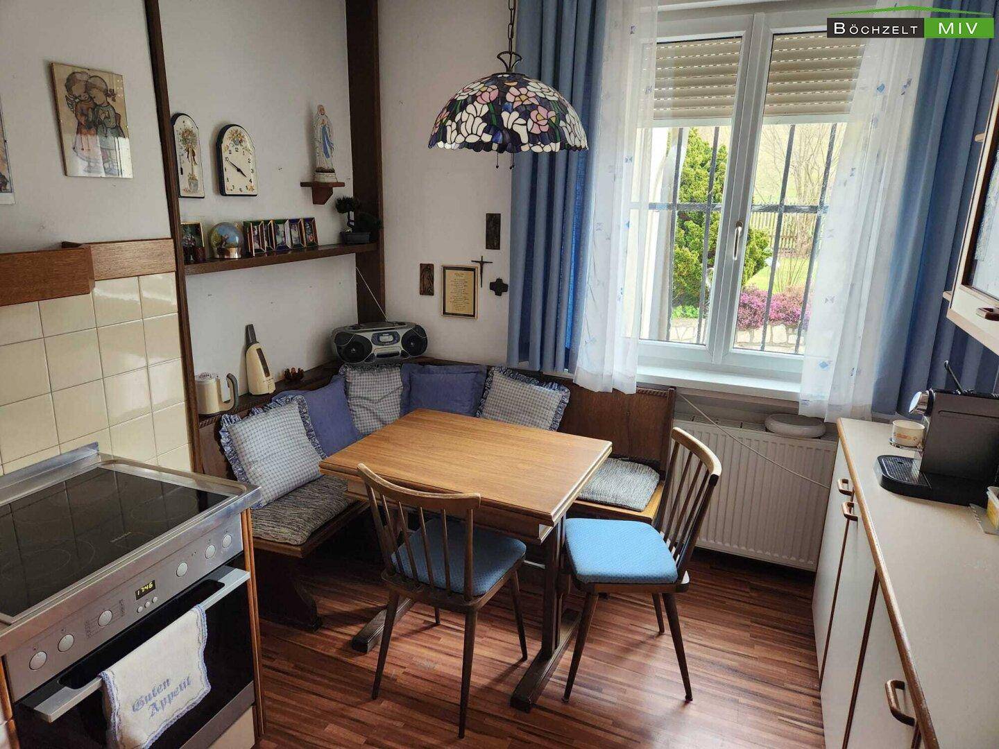 Gemütliche Wohnküche mit Essecke, Holzmöbeln und einem Fenster mit Blick ins Grüne.