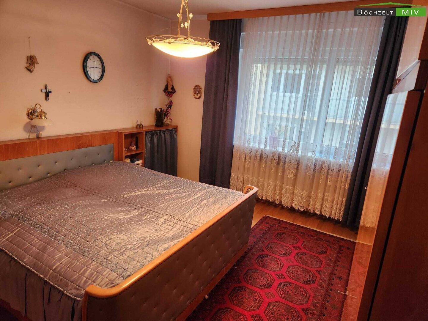 Schlafzimmer mit Doppelbett, Nachttischen und einem Teppich, in traditionellem Stil eingerichtet.
