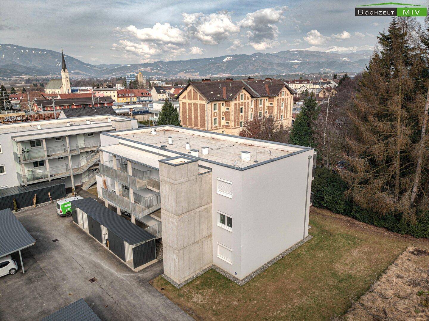 Luftaufnahme eines Wohngebäudes mit moderner Architektur und Bergblick im Hintergrund.