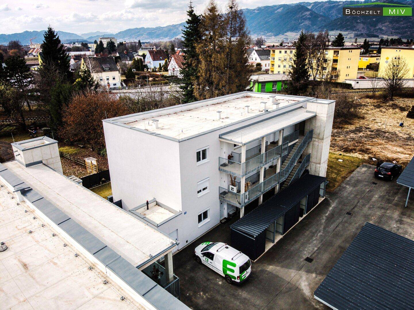 Luftaufnahme eines modernen Wohngebäudes mit Außentreppen und Carport-Anlagen.