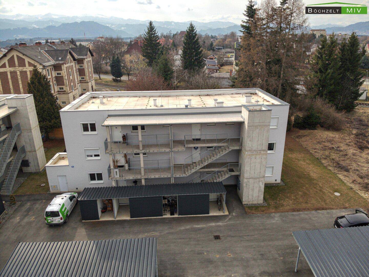 Luftaufnahme eines Wohngebäudes mit Außentreppen und Carports, umgeben von Natur.