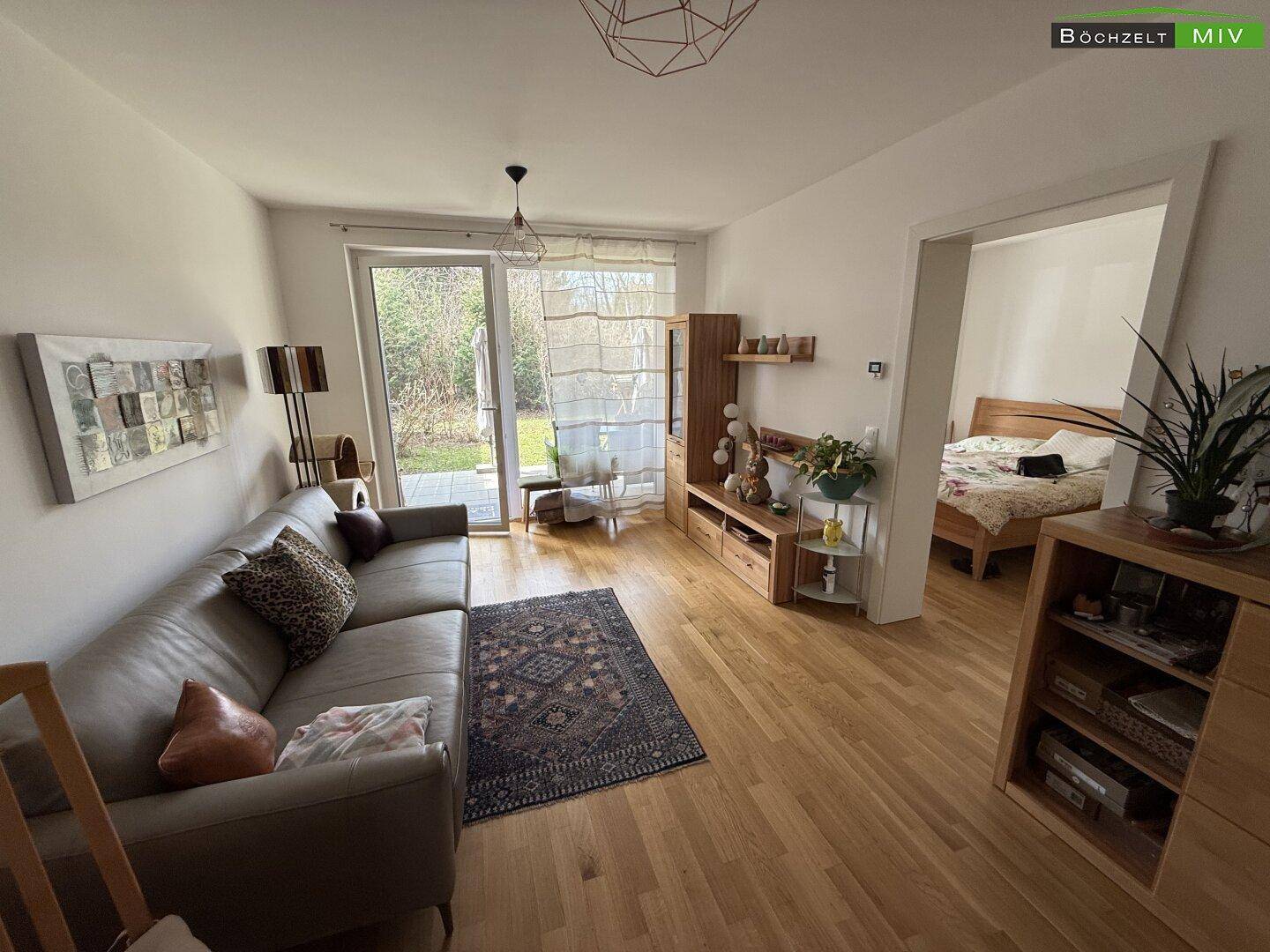 Wohnzimmer mit Holzfußboden und offenem Übergang zu einem angrenzenden Schlafzimmer.
