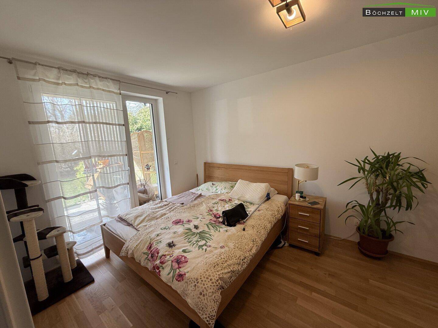 Gemütliches Schlafzimmer mit Holzfußboden, Doppelbett und direktem Zugang zum Garten.