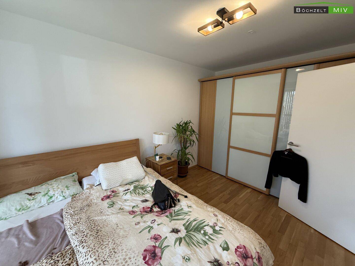 Schlafzimmer mit Holzfußboden, Doppelbett und praktischem Einbauschrank mit Schiebetüren.