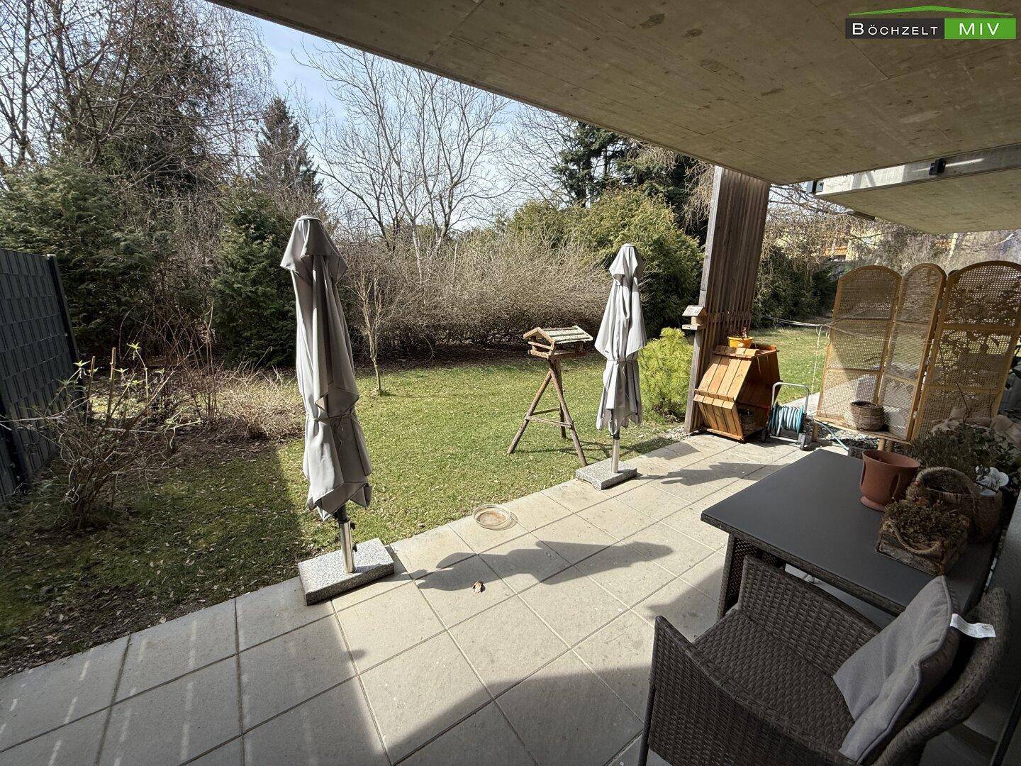 Überdachte Terrasse mit Gartenmöbeln und Blick auf den grünen Gartenbereich.