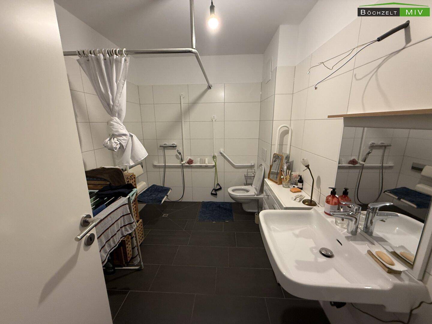 Geräumiges Badezimmer mit barrierefreier Dusche, WC und Haltegriffen.