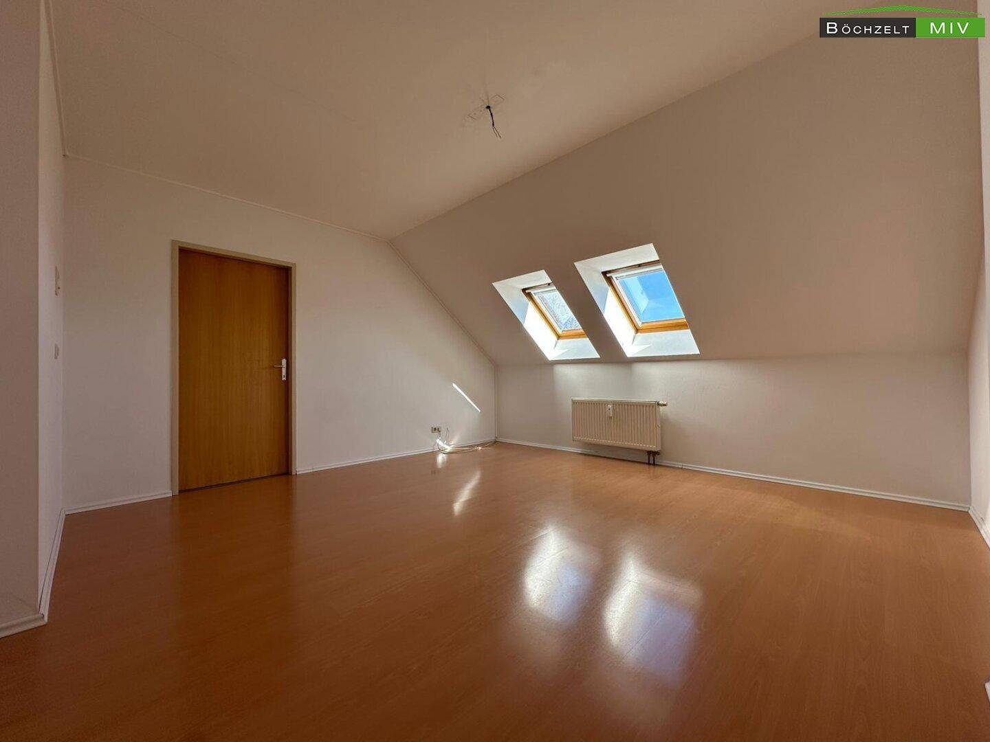 Geräumiger, heller Raum im Dachgeschoss mit Laminatboden und zwei Dachfenstern.