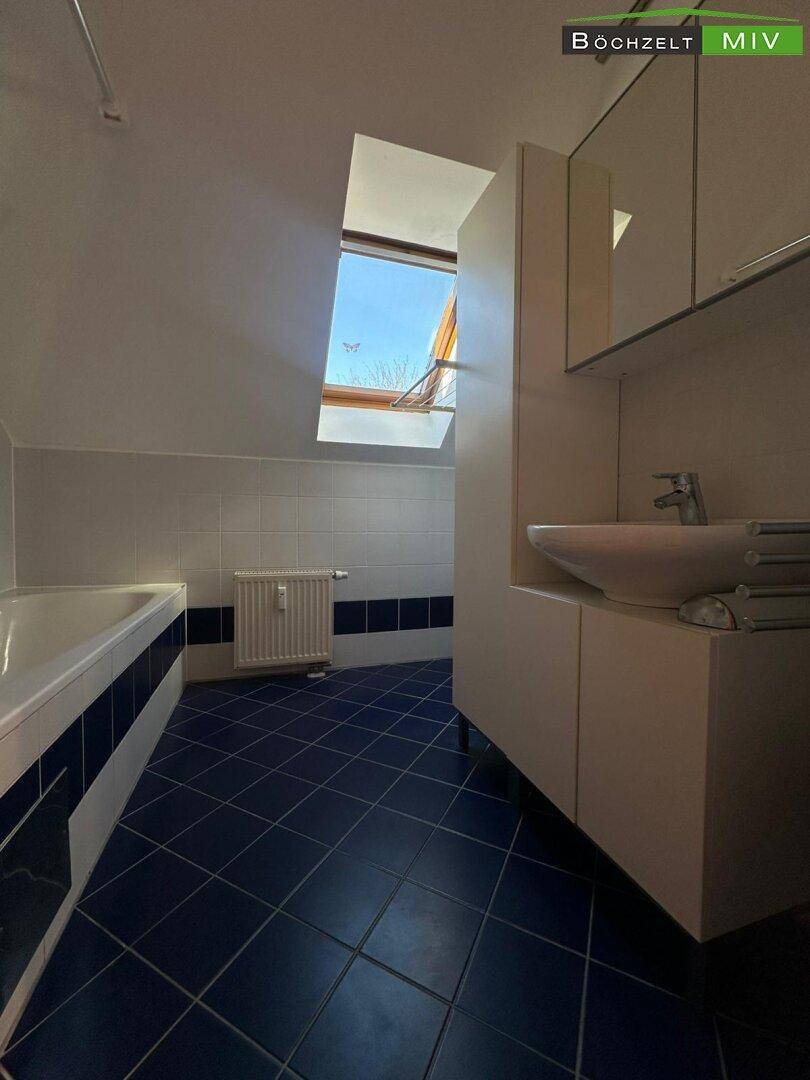 Helles Badezimmer mit Waschbecken, Spiegelschrank und Dachfenster.