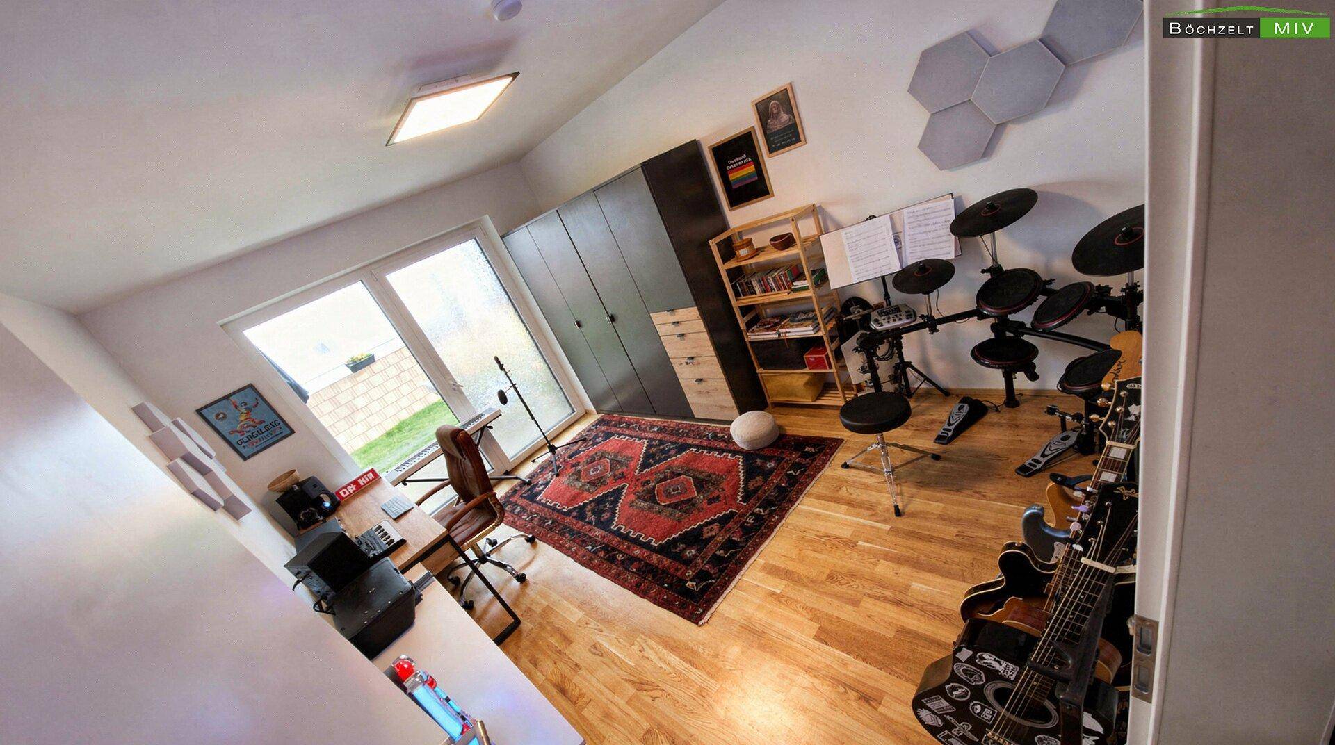Helles Zimmer mit Holzboden, Musikinstrumenten und Zugang zum Gartenbereich.