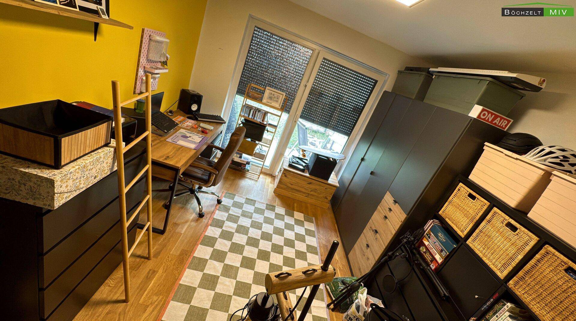 Helles Arbeitszimmer mit Schreibtisch, Stauraum und Zugang zum Außenbereich.
