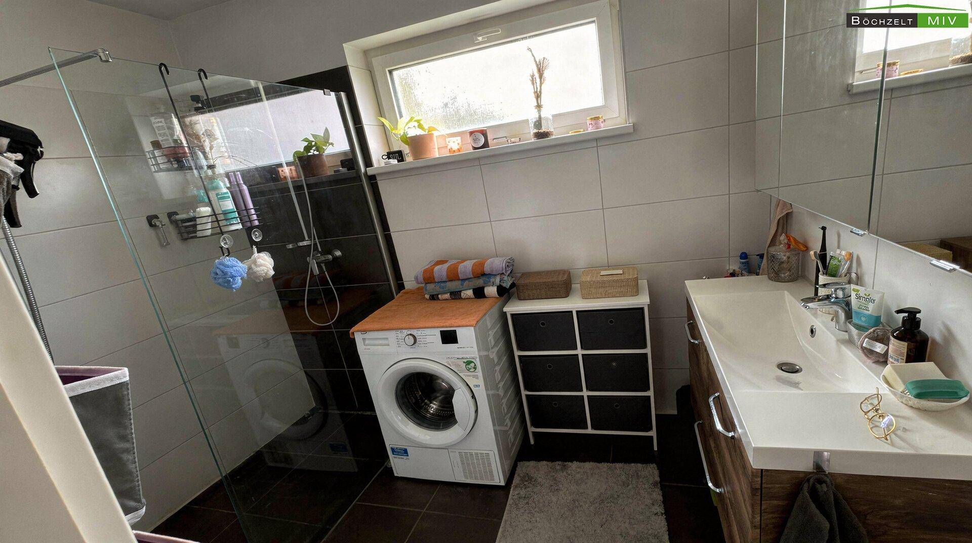 Modernes Badezimmer mit Dusche, Waschbecken und Fenster für Tageslicht.