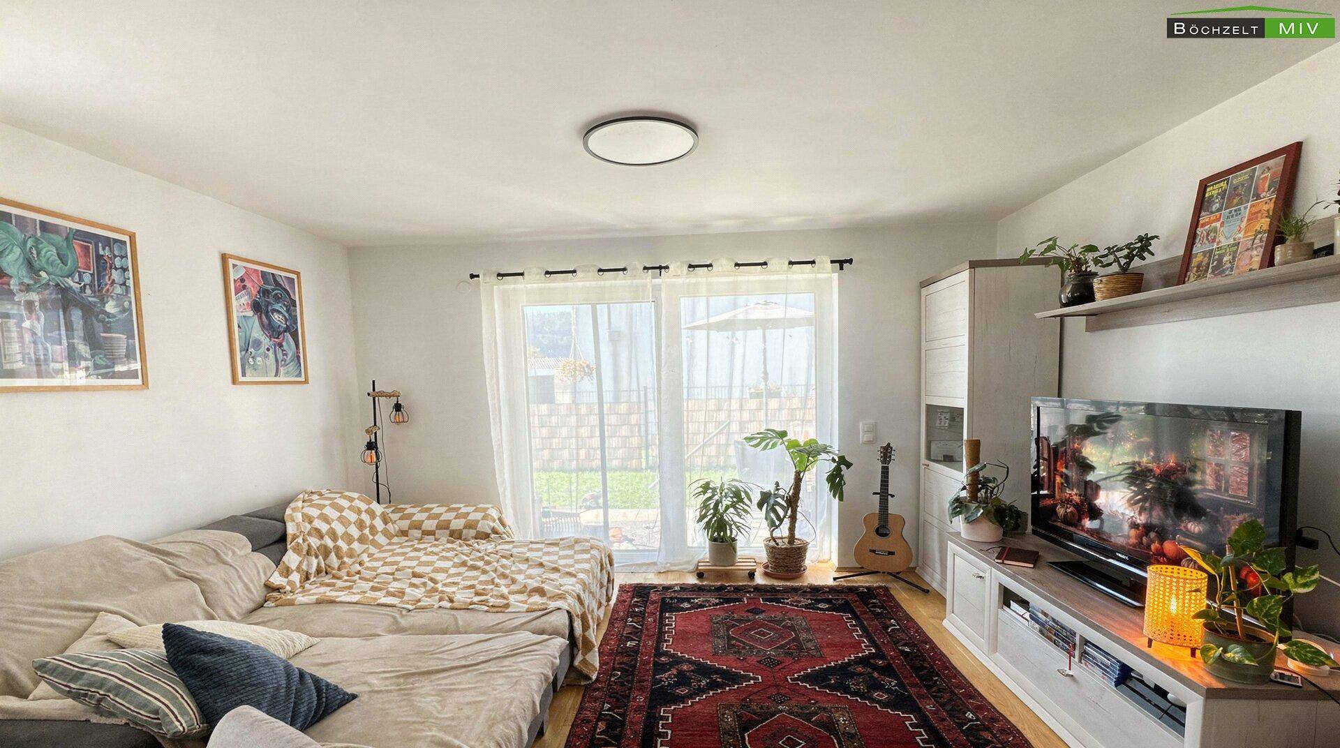 Gemütliches Wohnzimmer mit Sofa, Teppich und Zugang zur Terrasse oder Garten.
