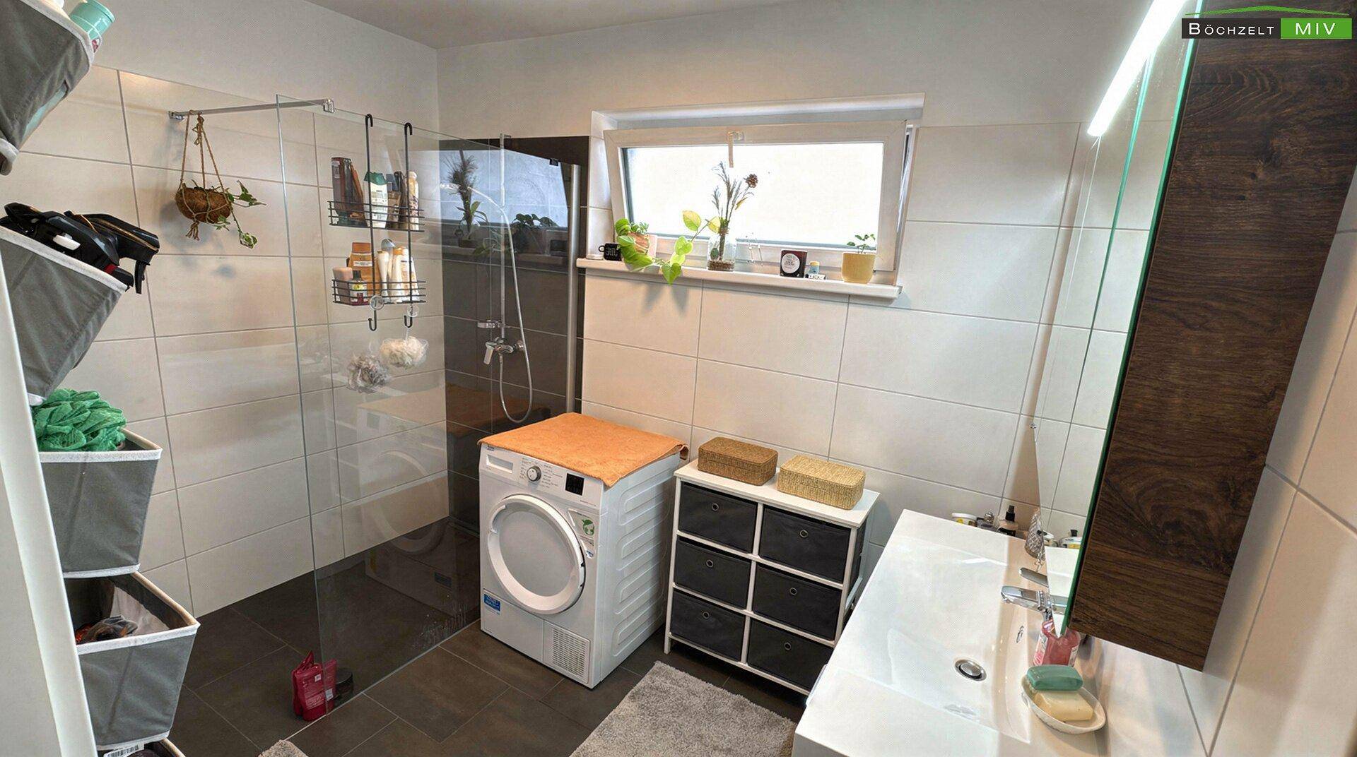 Modernes Badezimmer mit ebenerdiger Dusche, Waschmaschine und Fenster.