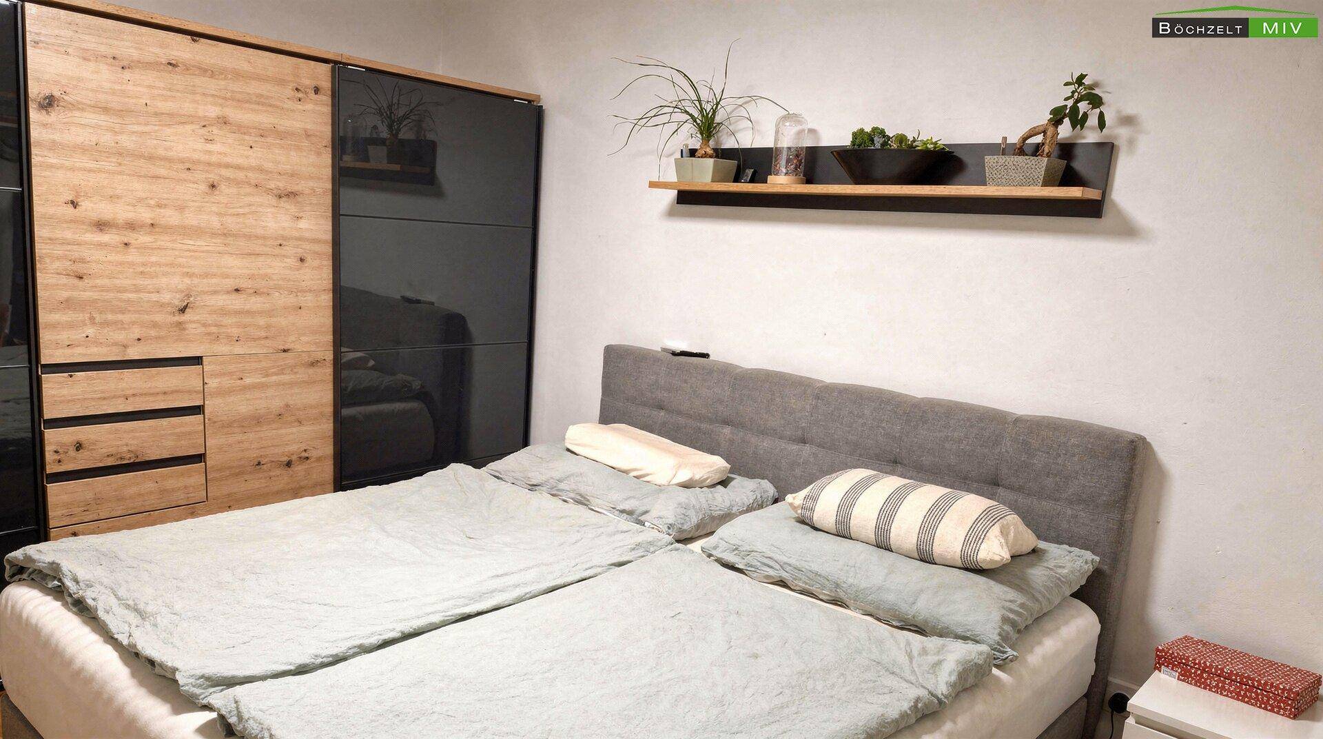 Modernes Schlafzimmer mit großem Bett, Schiebetürenschrank und Holzboden.