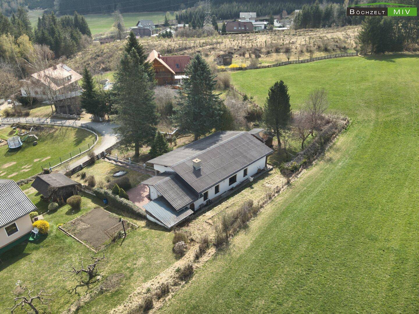 Weitläufige Luftaufnahme des Hauses mit umliegenden Feldern und Wäldern, eingebettet in eine grüne Landschaft.