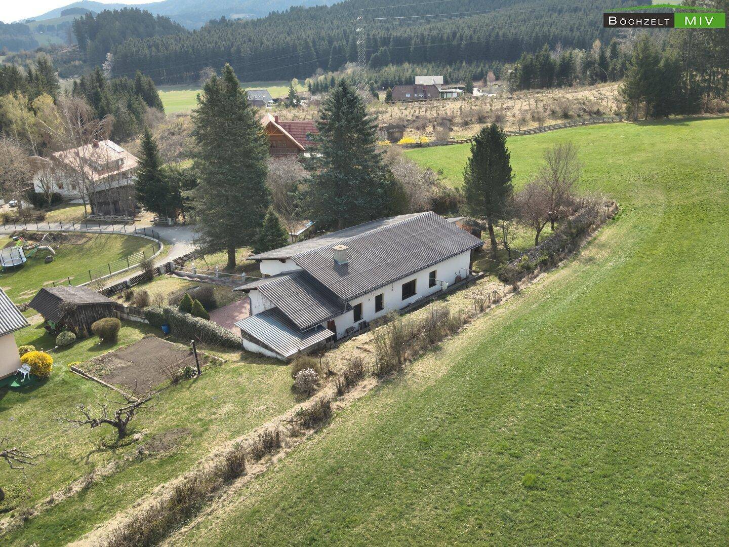 Panoramablick aus der Vogelperspektive auf das Anwesen, umgeben von grünen Wiesen und bewaldeten Hügeln.