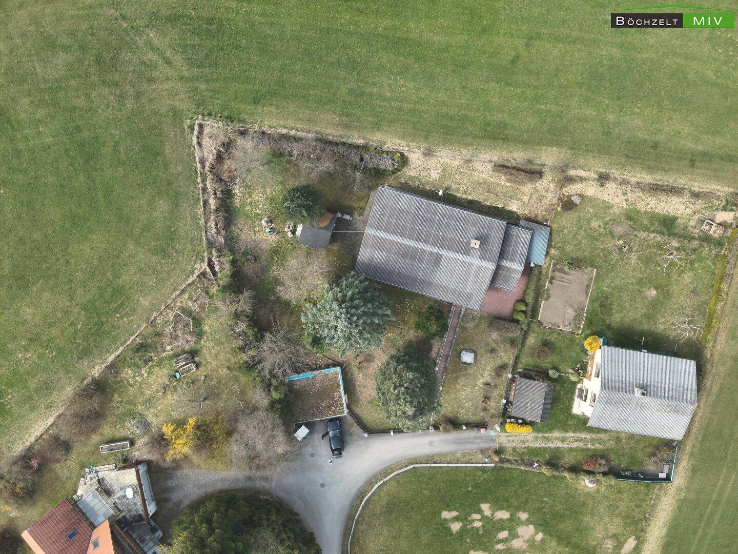 Senkrechte Luftaufnahme des Grundstücks mit Wohnhaus, Nebengebäuden und der umgebenden Gartenfläche.