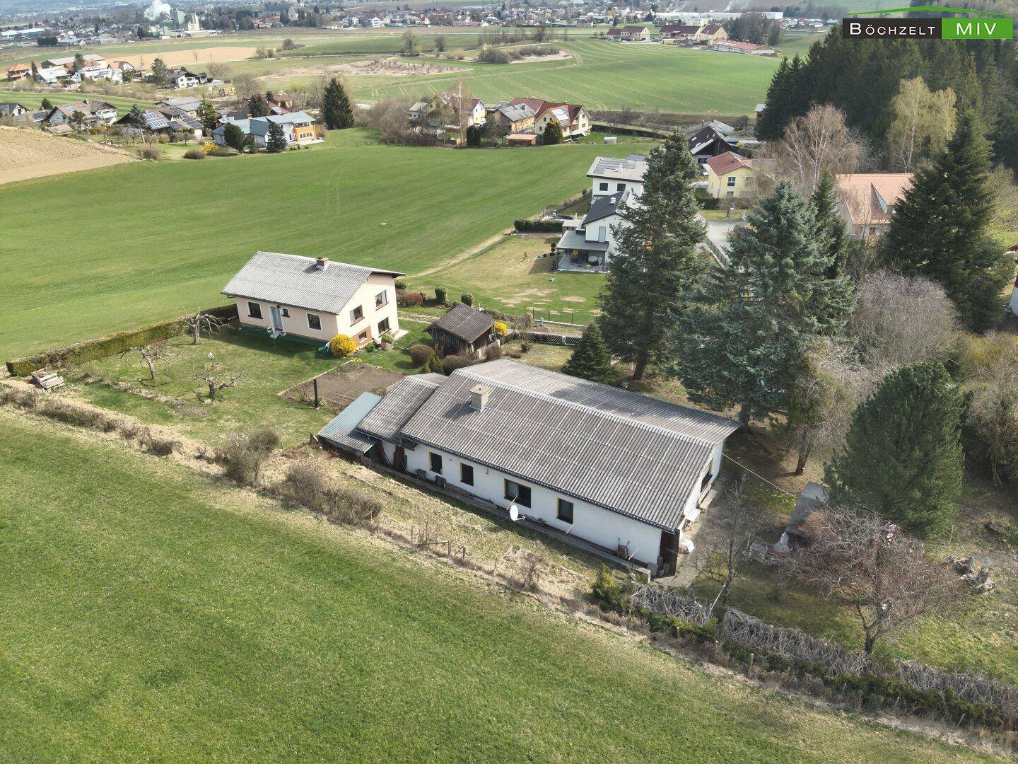 Luftaufnahme des Hauses und der Nachbarschaft, eingebettet in eine grüne Hügellandschaft mit Fernblick.