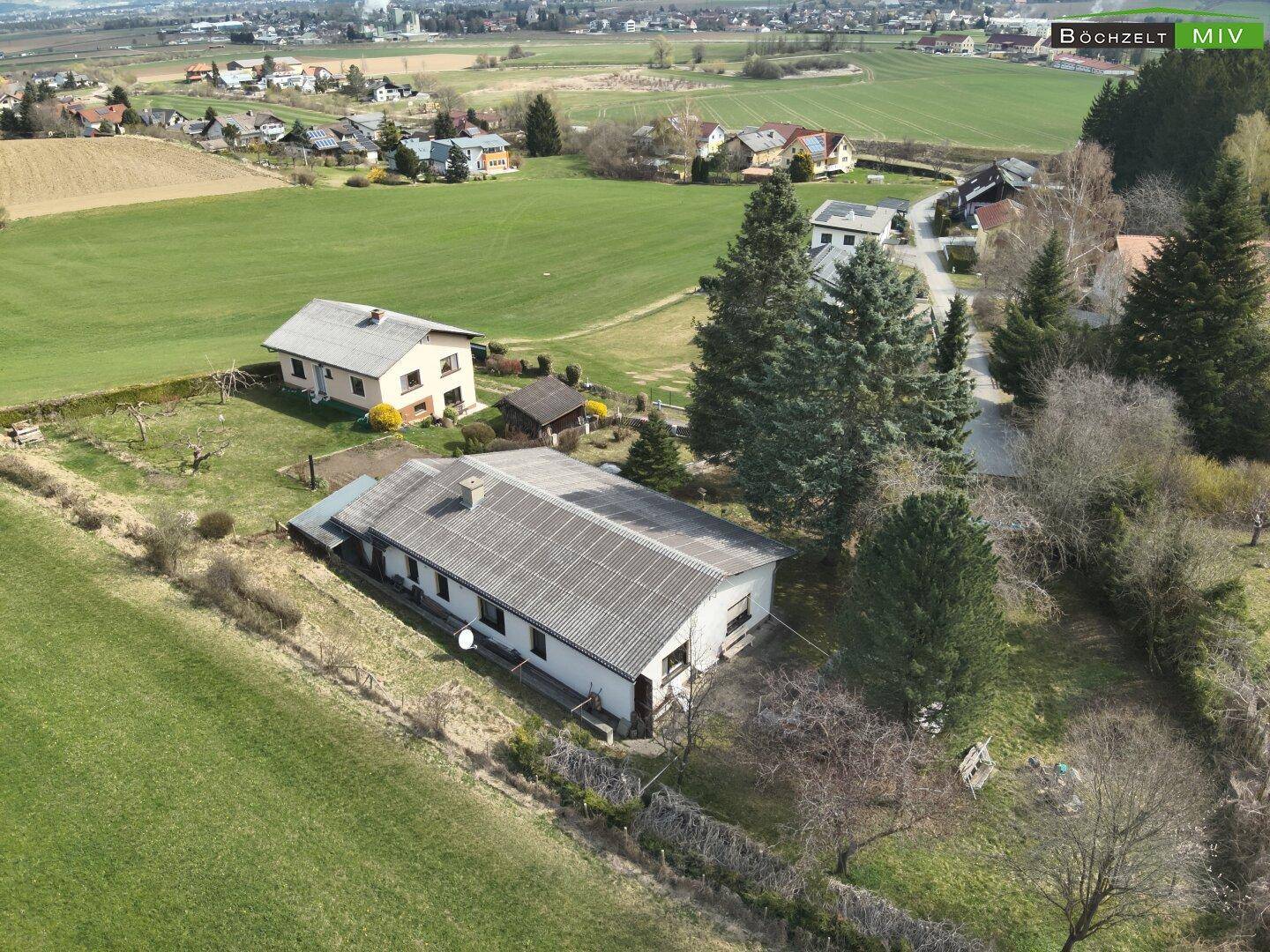 Luftaufnahme des Anwesens mit dem Wohnhaus und den Nachbarhäusern, umgeben von grünen Wiesen und Wäldern.