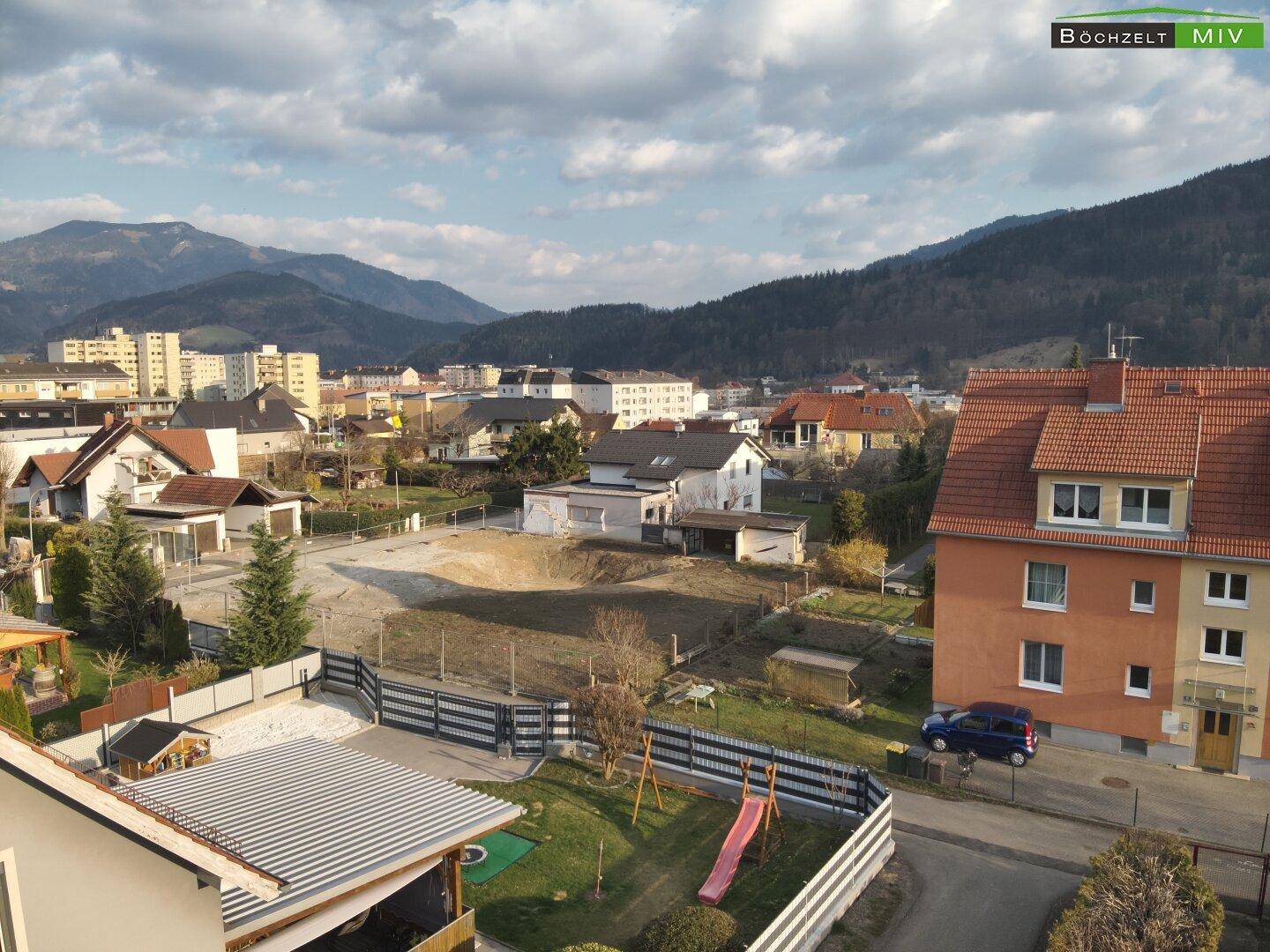 Panoramablick über die Wohngegend mit dem Baugrundstück und den Bergen am Horizont.
