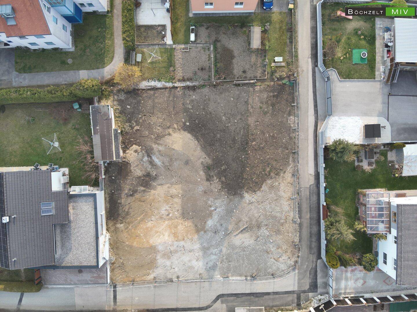 Senkrechte Luftaufnahme des unbebauten Grundstücks in einer städtischen Umgebung mit Straßen.