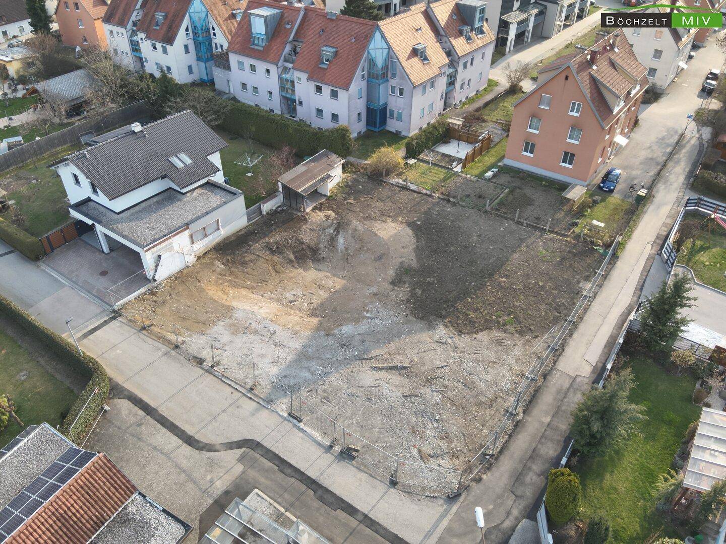 Luftaufnahme des Baugrundstücks mit angrenzenden Wohnhäusern und Straßen in der Umgebung.