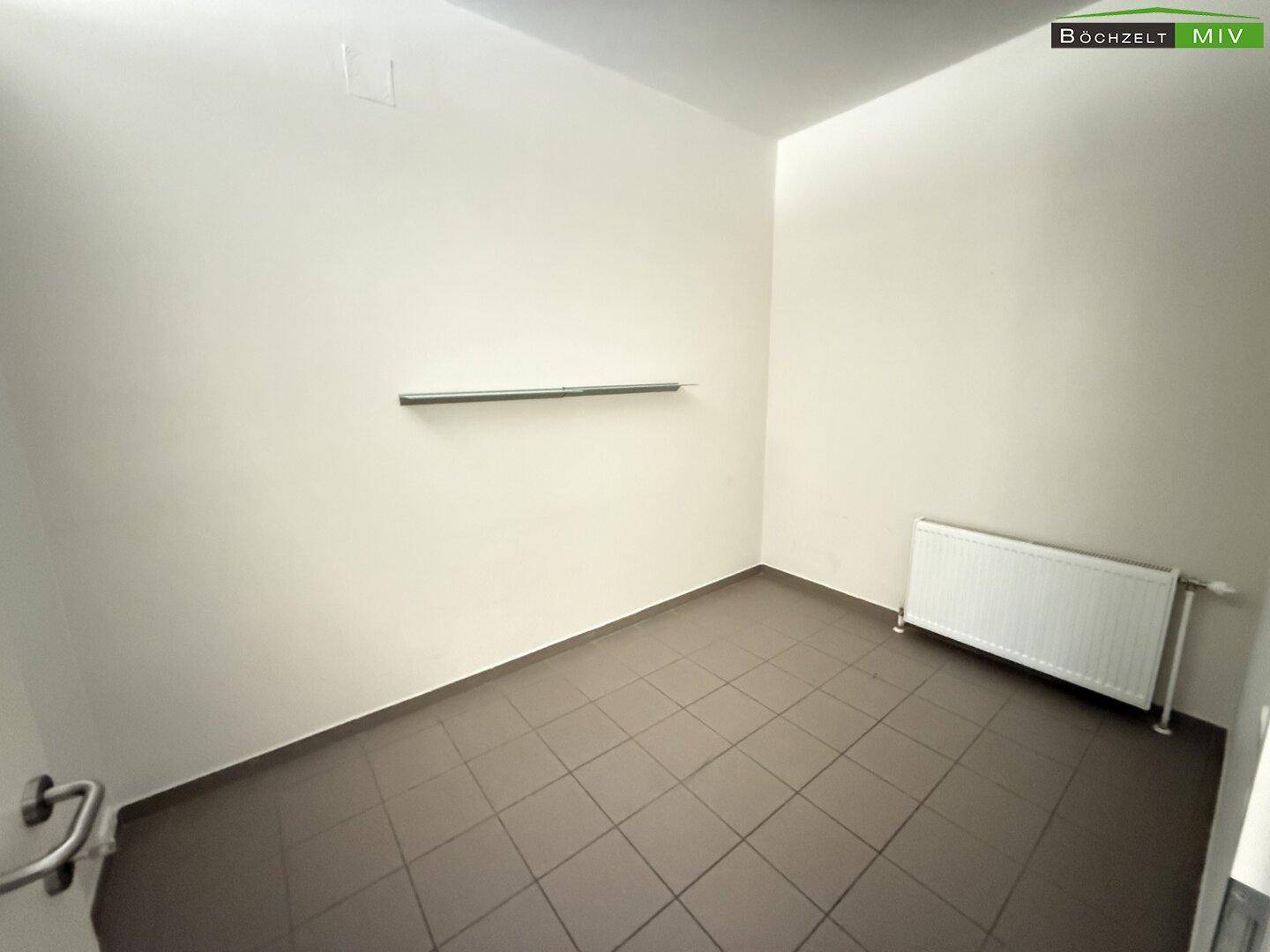 Kleiner Lagerraum mit Fliesenboden, weißen Wänden und einem Heizkörper an der Wand.