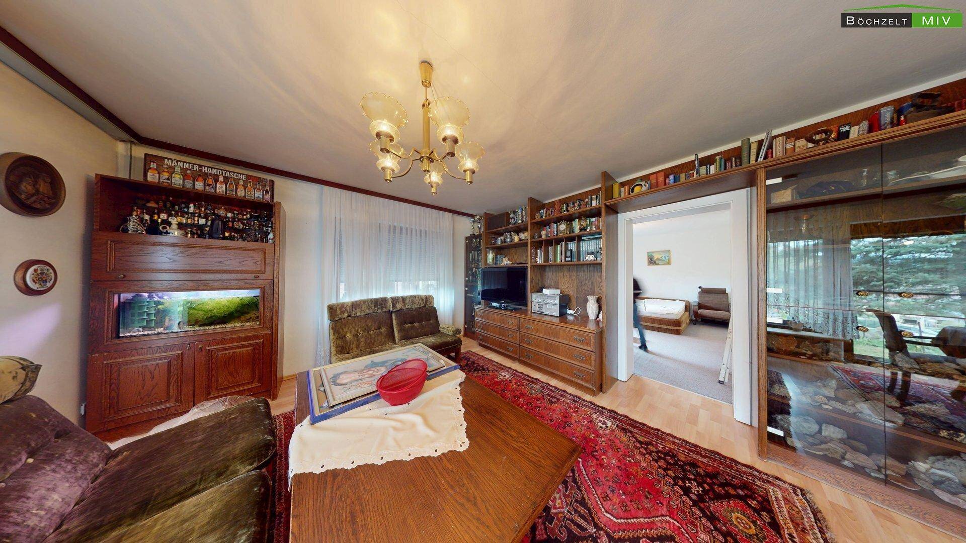 Gemütliches Wohnzimmer mit Holzmöbeln, großem Bücherregal und Teppich, ideal zum Entspannen.