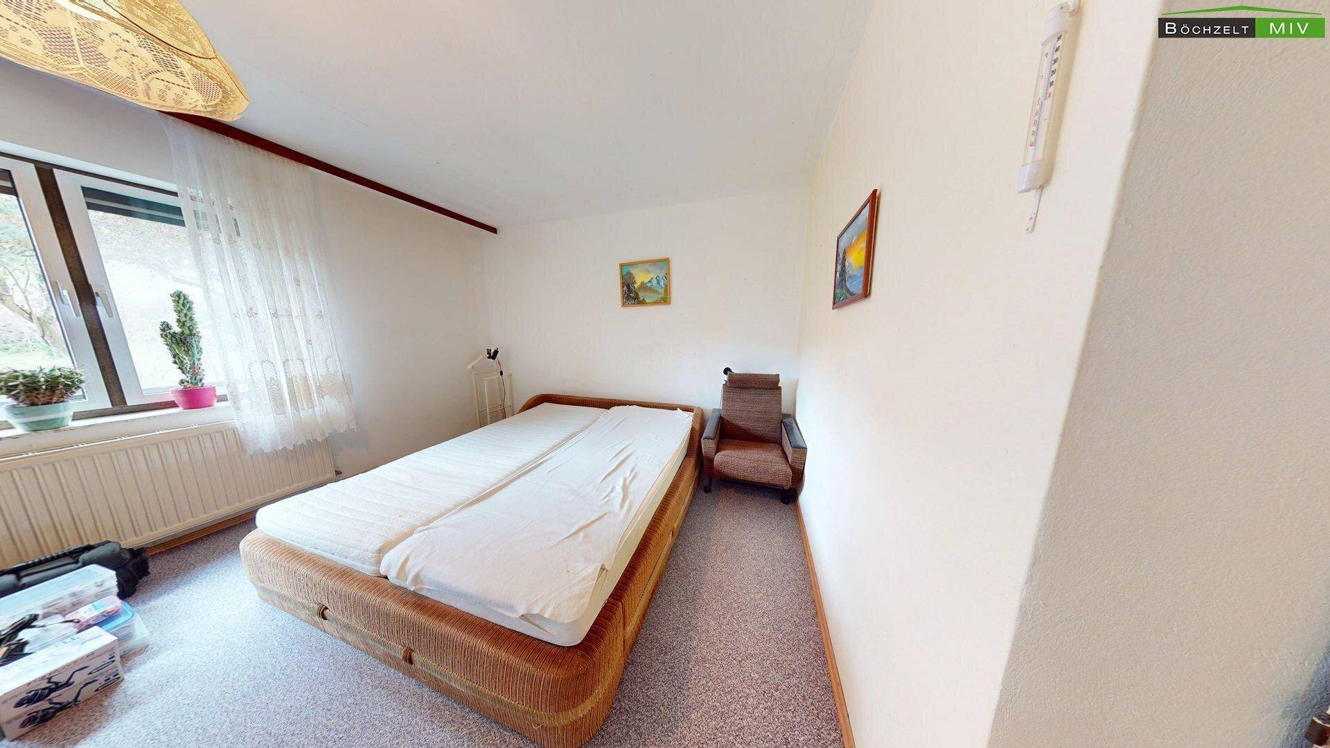 Schlafzimmer mit Teppichboden und großem Fenster, das viel Tageslicht hereinlässt und eine ruhige Atmosphäre schafft.