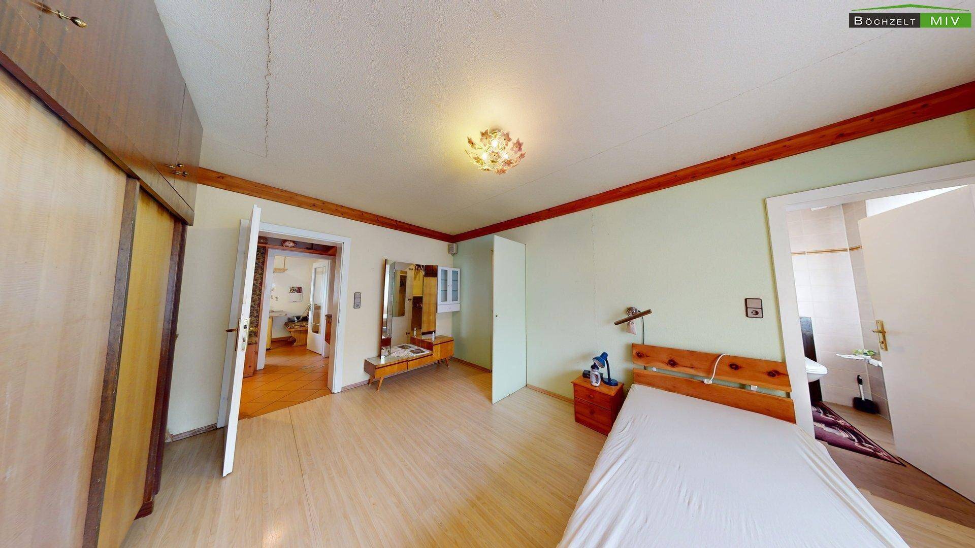 Schlafzimmer mit Laminatboden und großem Fenster, das viel Tageslicht hereinlässt und eine angenehme Atmosphäre schafft.