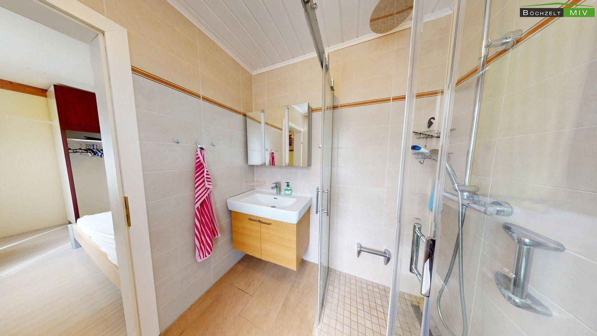 Helles Badezimmer mit Duschkabine, modernem Waschbecken und Wand-WC, ausgestattet mit hellen Fliesen.
