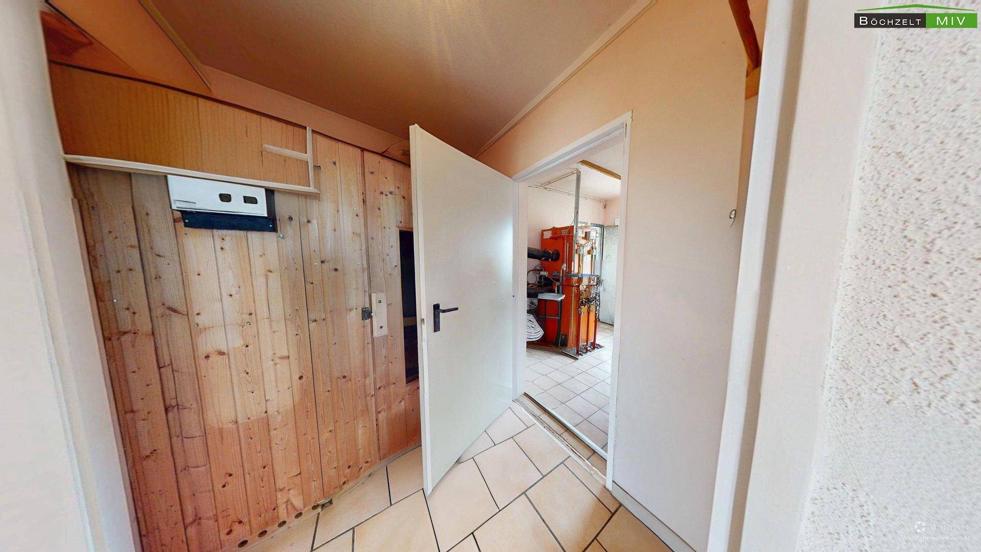 Eingangsbereich zu einem Technikraum mit Holzverkleidung, der zu einem Heizraum führt.
