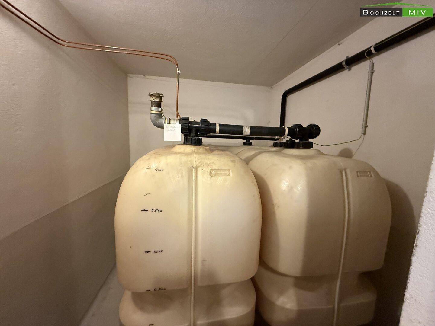 Technikraum mit zwei großen Wassertanks und Rohrleitungen, für die Wasserversorgung des Hauses.