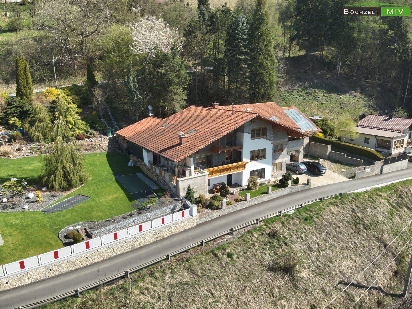 Seitenansicht des Hauses mit weitläufigem Rasenbereich und dekorativer Steinmauer.