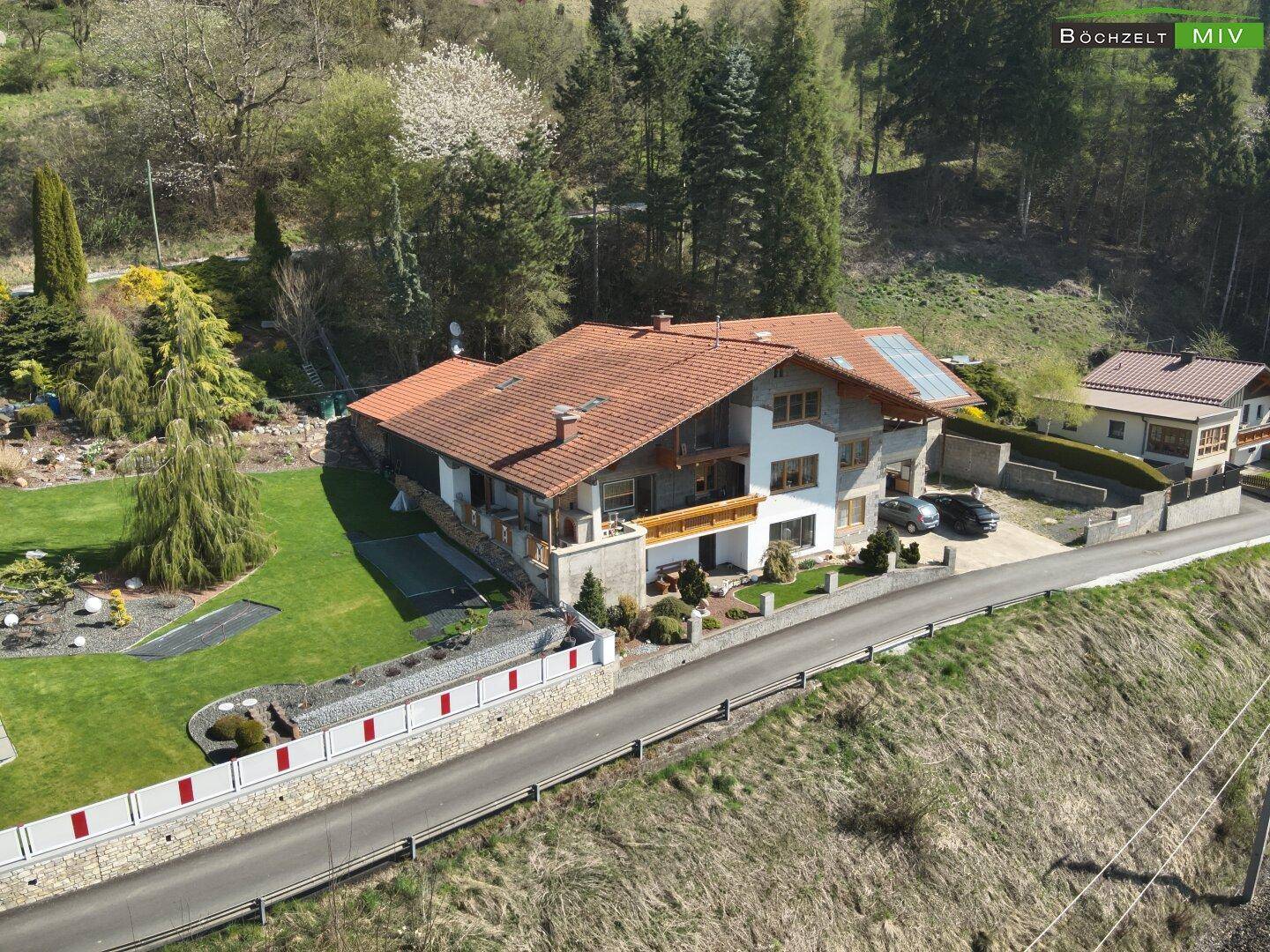 Seitenansicht des Hauses mit weitläufigem Rasenbereich und dekorativer Steinmauer.