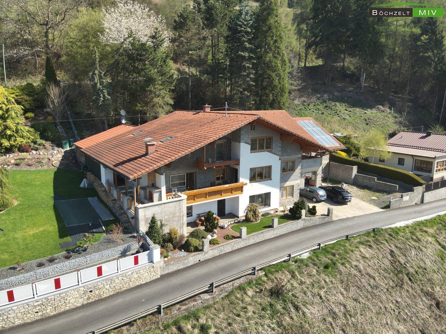 Seitenansicht des Hauses mit weitläufigem Rasenbereich und dekorativer Steinmauer.
