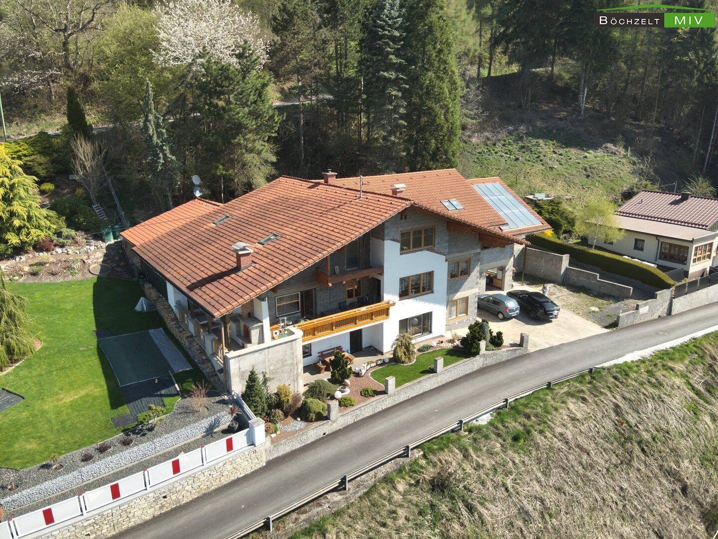 Seitenansicht des Hauses mit weitläufigem Rasenbereich und dekorativer Steinmauer.