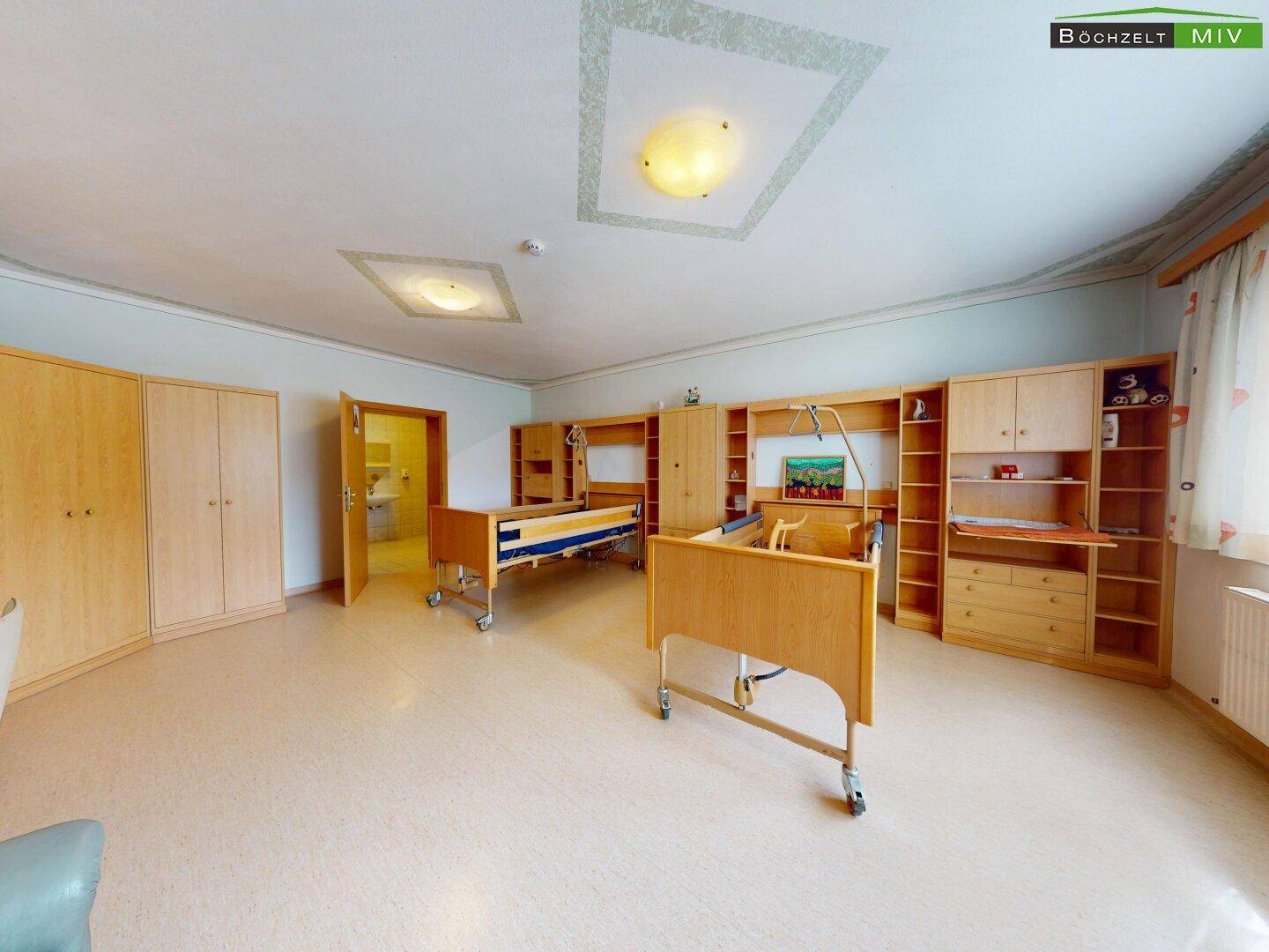 Geräumiges Schlafzimmer mit zwei Pflegebetten, Holzschränken und hellem Bodenbelag.