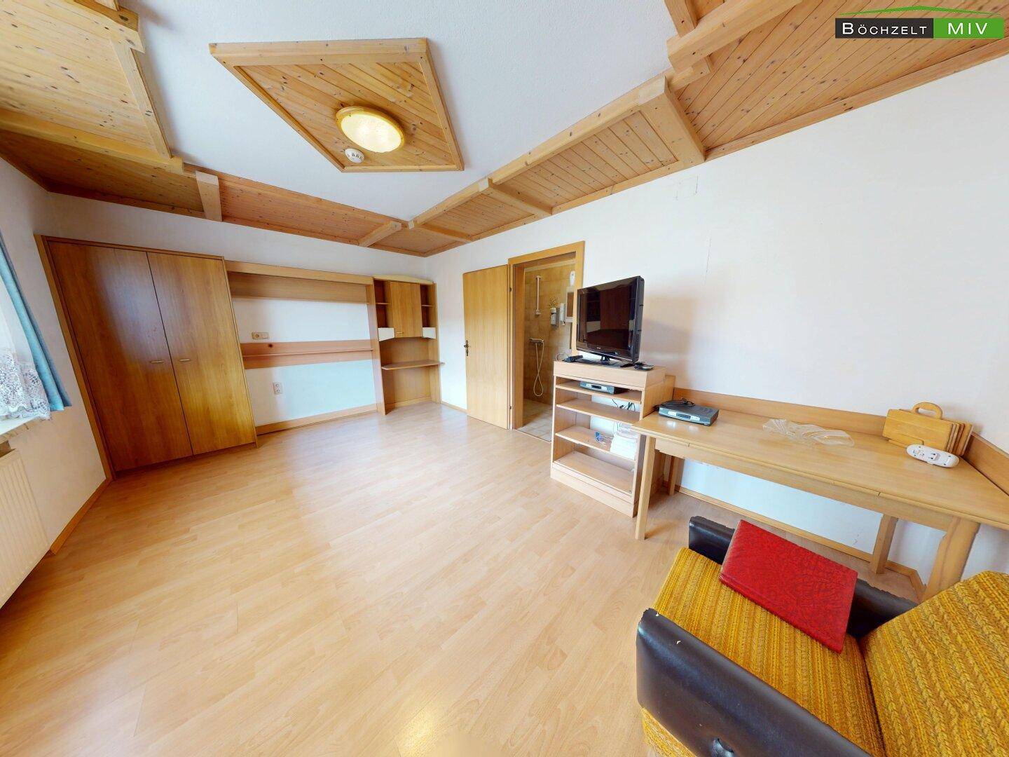 Gemütliches Schlafzimmer mit Holzdecke, Laminatboden und funktionalen Holzmöbeln.