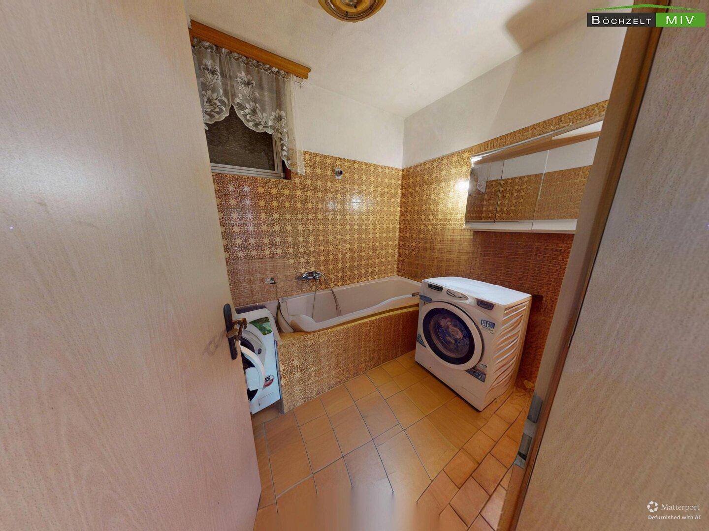 Badezimmer mit gemusterten braunen Fliesen, Badewanne und einer Waschmaschine.