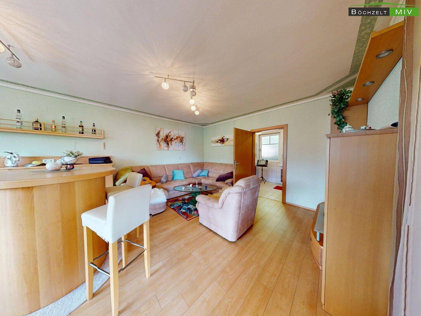Gemütliches Wohnzimmer mit Ecksofa, Barbereich und hellgrünen Wänden.