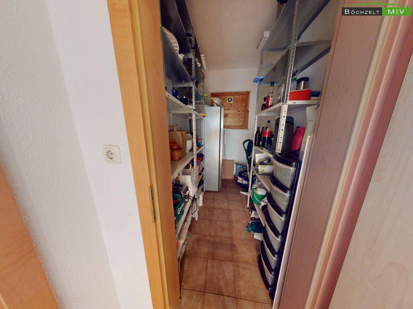 Gut organisierte Speisekammer mit Metallregalen und einem Kühlschrank.