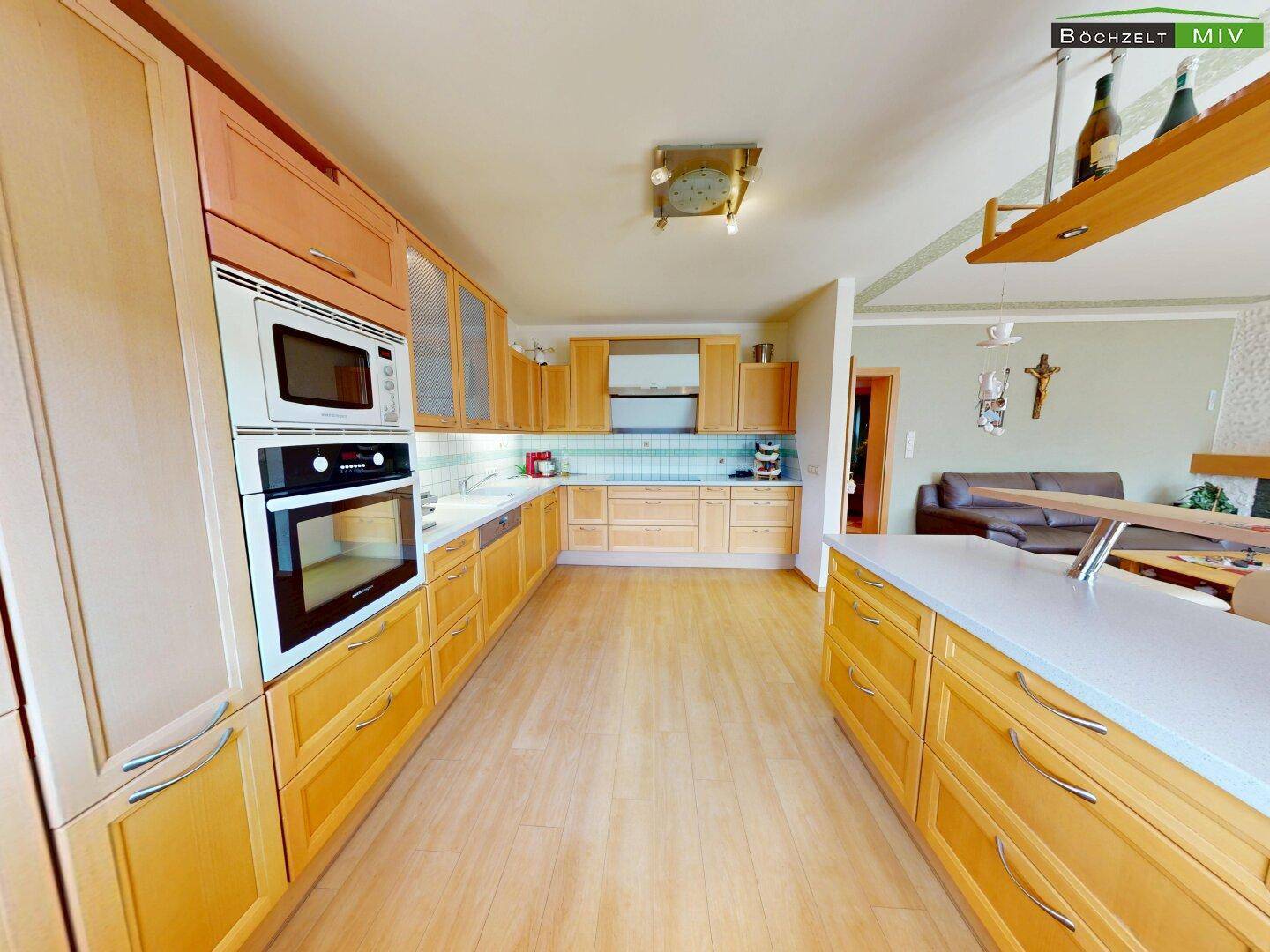 Geräumige Holzküche mit modernen Einbaugeräten und Blick in den angrenzenden Wohnbereich.